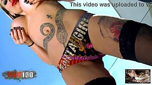 Tattooed blonde milf with huge fake boobs performs a seductive striptease, slowly undressing to reveal her curves.