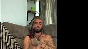 dreddy the emo punk dude with tattoos and alternative hairstyle strokes his cock solo in a casual scene