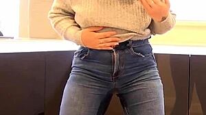 A person pees in their jeans pants, creating a wet spot.