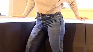 A person pees in their jeans pants, creating a wet spot.