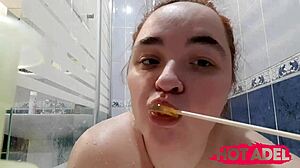 Chubby teen sucks candy while fingering fat pussy in shower