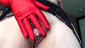 mature woman with big clit strips and touches her shaved pussy in red gloves.