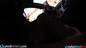 Brunette in black pantyhose displaying her feet from the car