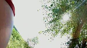 Seductress performs striptease by the lake at sunset