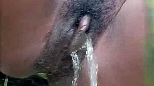 Horny ebony woman pisses publicly in wet outdoor spot